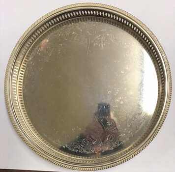 Large circular silver tray with engraving at centre.
