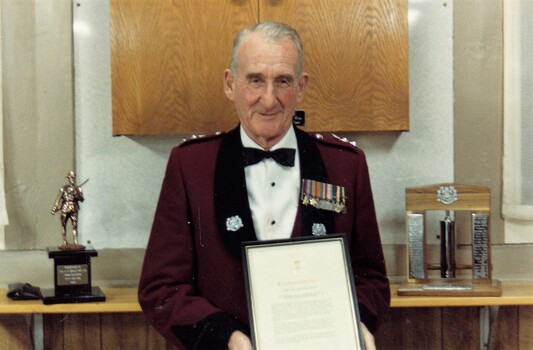 Soldier in formal uniform holding framed certificate