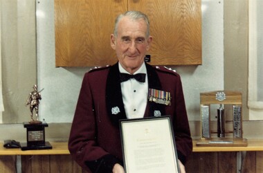 Soldier in formal uniform holding framed certificate
