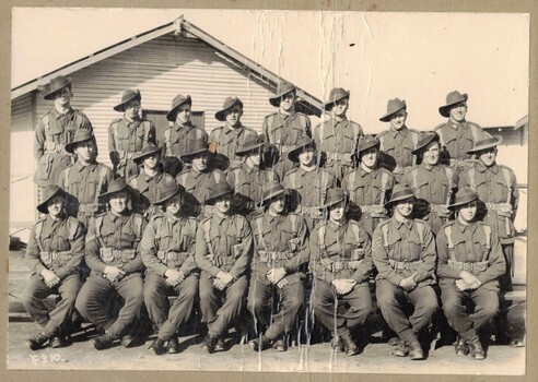 Three rows of soldiers in front of hut.