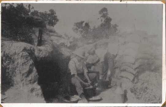Soldier preparing food in sandbagged trench.