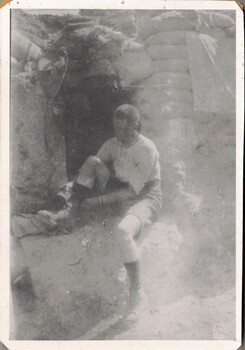 Soldier putting on his boots in trench.