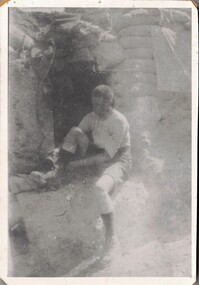 Soldier putting on his boots in trench.