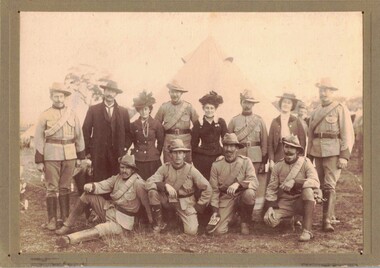 Soldiers and several ladies in front of tent.
