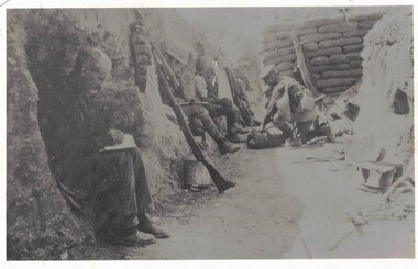 Soldiers in a trench, one man writing