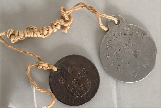 Two small metal objects with writing stamped on them.
