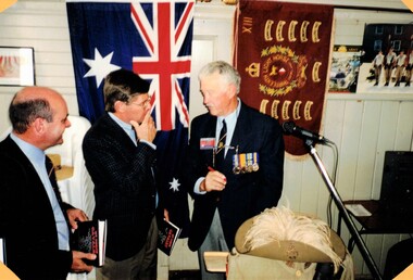 Three men standing in front of flags.
