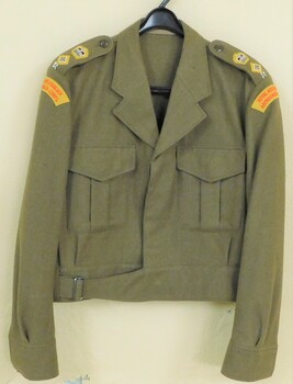Khaki army jacket with yellow patches on sleeves.