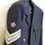 Jacket sleeve with embroidered crown over silver stripes.