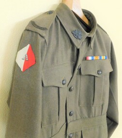 Khaki jacket with colour patch on sleeve.
