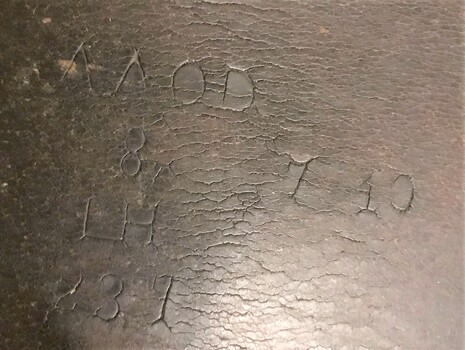 Piece of leather with letters and numbers stamped on it.