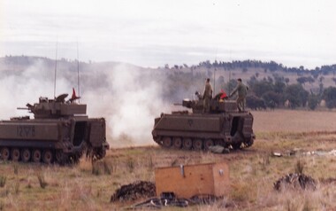 Two tanks on a hillside, firing guns.