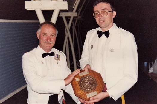 Two soldiers exchanging a shield trophy
