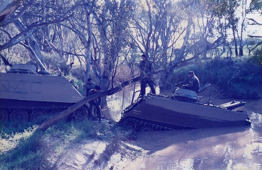 Tank towing another out of a creek