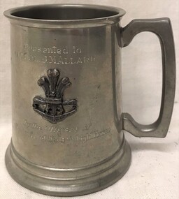 A metal mug with a badge on the side.