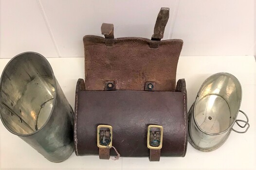 Two tin cups beside open leather case