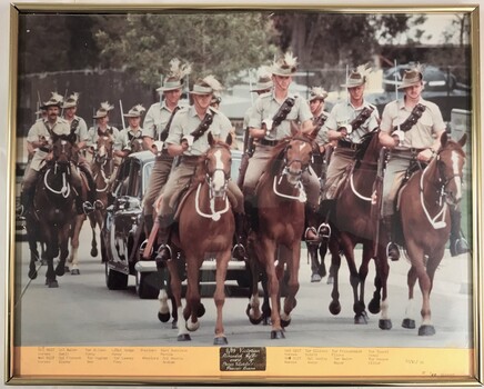 Soldiers on horses gathered round a car.
