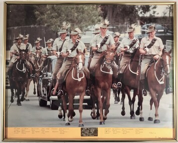 Soldiers on horses gathered round a car.