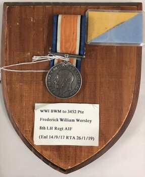 Wooden plaque with medal and paper label