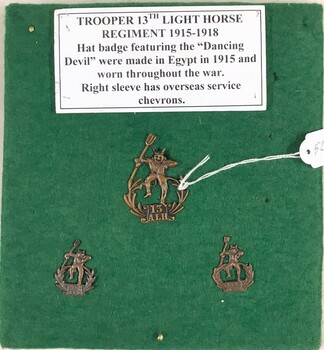Cloth covered board with three small badges on it.