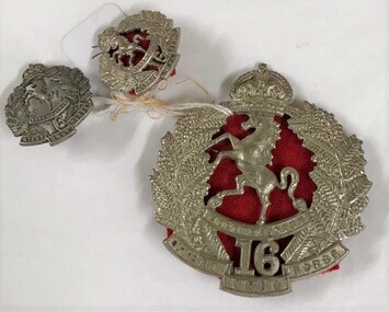 One large metal badge with two smaller ones attached with string.