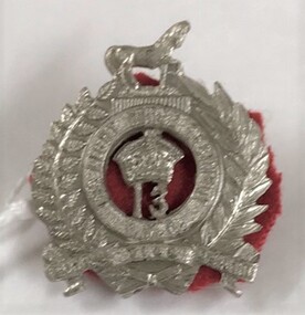 Small metal badge surmounted by horse
