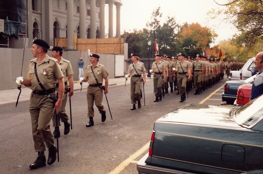 Soldiers with swords marching passed a building