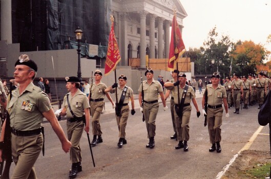Soldiers marching , some carrying flags.