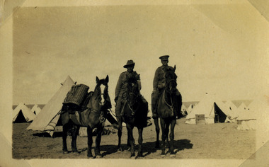 Soldiers on horses posing in camp