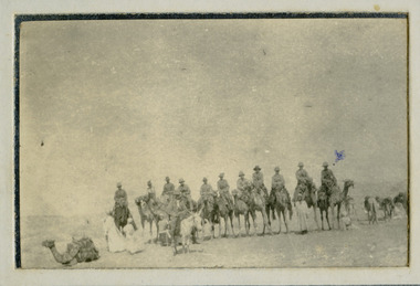 soldiers on camels with natives