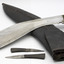 Detail showing blade and two smaller blades unsheathed from scabbard. Scabbard has two small holes at opening for smaller blades