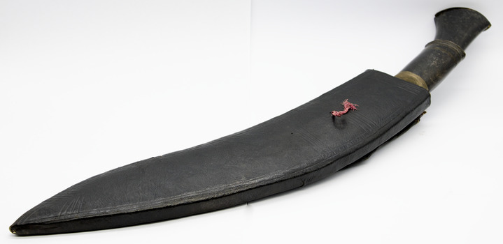 Dark brown leather scabbard with handle in background, pointed end towards viewer. Laying flat on white background