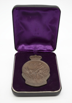 Bronze medallion with depiction of Simpson and his donkey, 1915. In purple, fabric-lined hinged box, opened. Object on white background