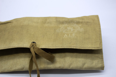 Tan coloured canvas wallet, closed, with white, printed AIF rising sun logo on top right. Two string fastener. On white background