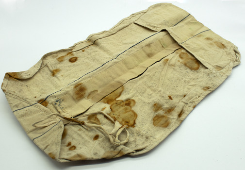 White linen fabric roll/pouch with 2 string fastners on one end and small pocket at the other. Has stains, possibly rust or blood speckles. Opened out on white background