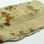 White linen fabric roll/pouch, rectangle shape.  Has stains, possibly blood or rust speckles. Opened out on white background