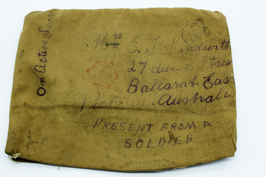 Khaki fabric, rectangular shape, with handwritten text in black ink, showing Ballarat East address, like an envelope. Also has official postage ink stamps, one red ink, one black.. 