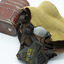 Khaki covered mask with black rubber head straps, same fabric covered tube from base of mask to top of tin canister. Canister is red/brown colour oval shape, lying with base visible on white background.