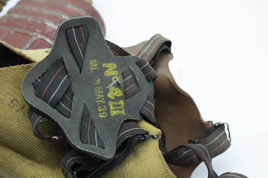 Back of gas mask is black rubbber head straps with black, red and white striped strapping. Yellow printed inscription on four-point connecting rubber piece, reads: N-4II / ML M MAY 39