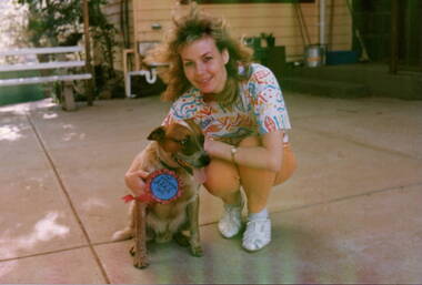 A lady is in a court yard with her dog.