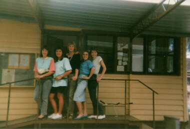 Four ladies standing on a landing in front of a doorway.