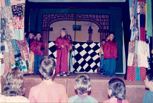 Six children in Chinese costumes are performing on a stage.