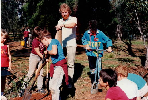 Children working in a garden under adult supervision.