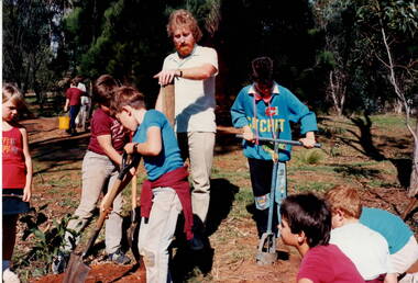Children working in a garden under adult supervision.