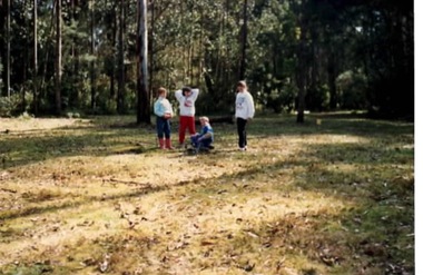 Four children in a bushland setting attempting to build a camp fire.