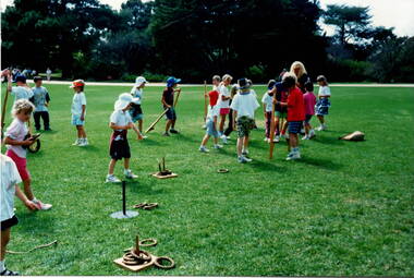 A group of children are playing coits on the lawns at Werribee Park Mansion.