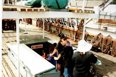Five children with an adult are going below decks on a ship. A lot of the ship's rigging is visible on the RHS of the image.