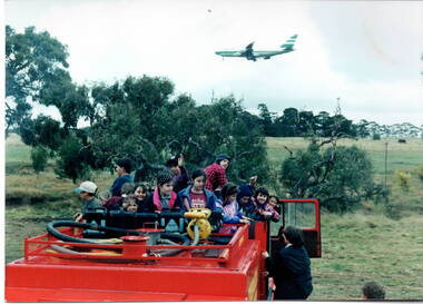 A group of children are preparing to be taken for a ride on a fire truck.