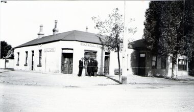 A photograph of a the original single story Royal Hotel in Sunbury showing the original corner entrance and three men standing beside it in the street.