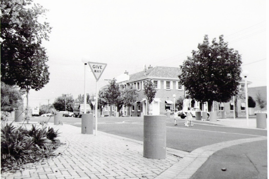 A streetscape of an intersection with a two storey brick building on one corner